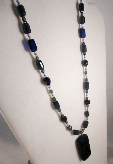 photo of necklace made by Homegrown Crafts featuring carved black cinnabar centerpiece and blue multi color bead strand
