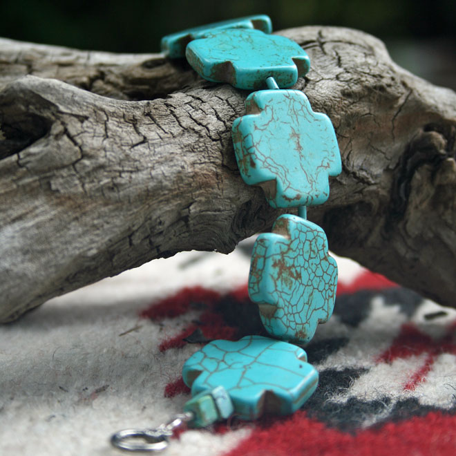 close up of Blue Cross Bracelet displayed on driftwood