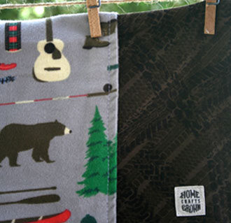 photo of reversible toddler blanket made by Homegrown Crafts featuring grey flannel camping print and brown cotton tire track print