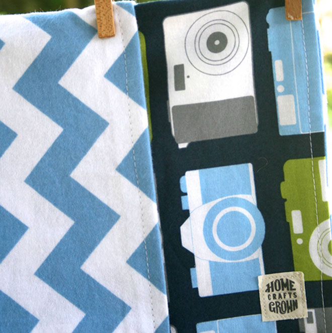 reversible toddler blanket made by Homegrown Crafts featuring flannel blue and white chevron print and cotton multi colored camera print