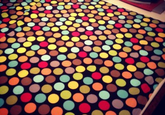 blanket fabric with multi colored dots and iron in the background