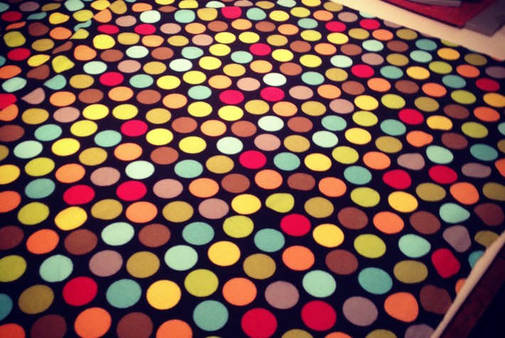 blanket fabric with multi colored dots and iron in the background